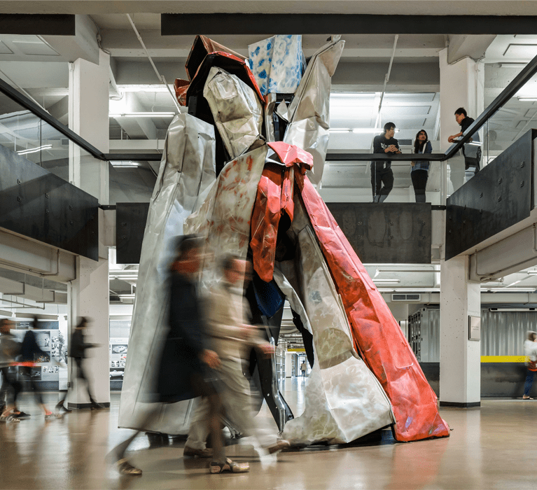 people walking by an automotive parts sculpture in the Taubman Center